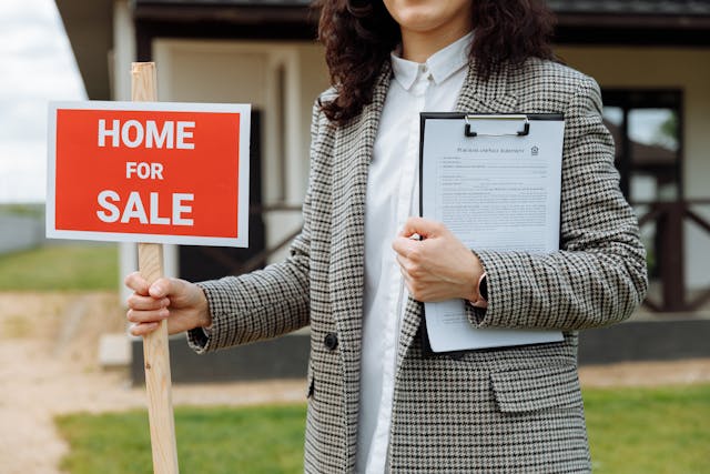 real estate agent holding a red home for sale sign